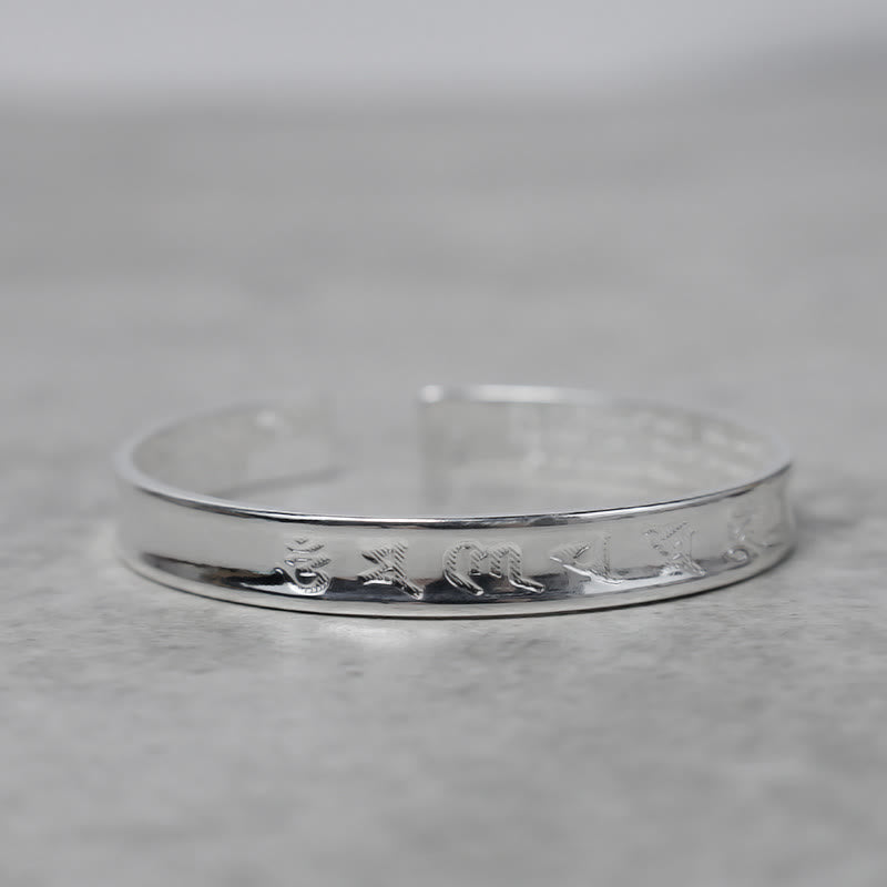 Silbernes Tibet Mantra Armband Flat Lay auf Marmor Oberfläche