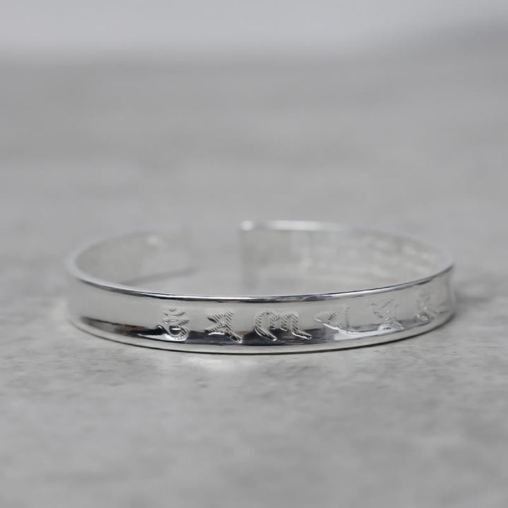 Silbernes Tibet Mantra Armband Flat Lay auf Marmor Oberfläche