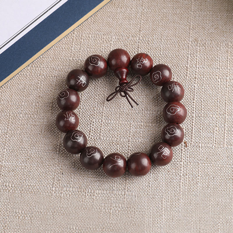 Dunkelbraunes Sandelholz Armband mit Om Symbol Perlen auf Leinenstoff.