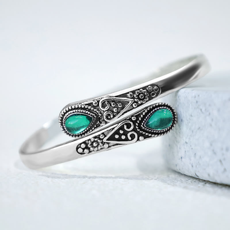 Silbernes Armband mit grünen Malachit-Steinen auf weißem Marmor, Heilung & Balance.