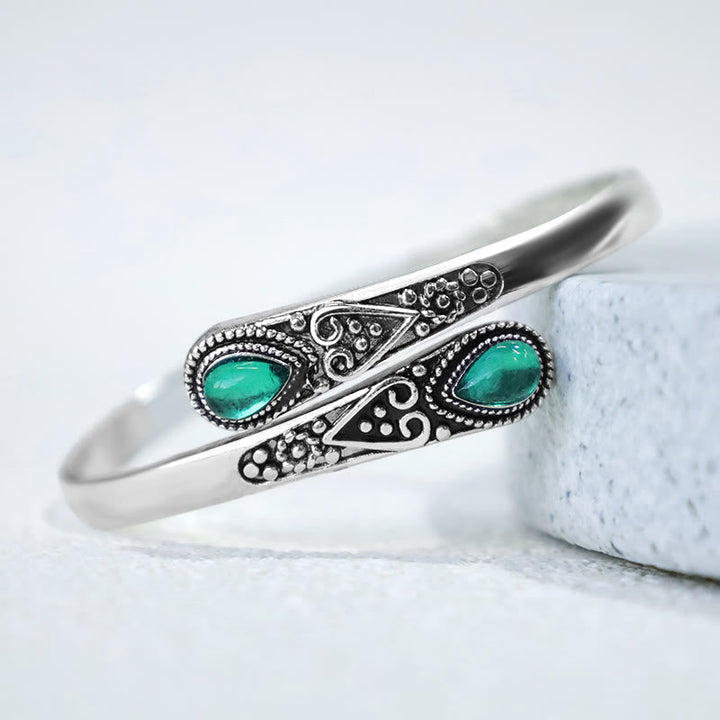 Silbernes Armband mit grünen Malachit-Steinen auf weißem Marmor, Heilung & Balance.
