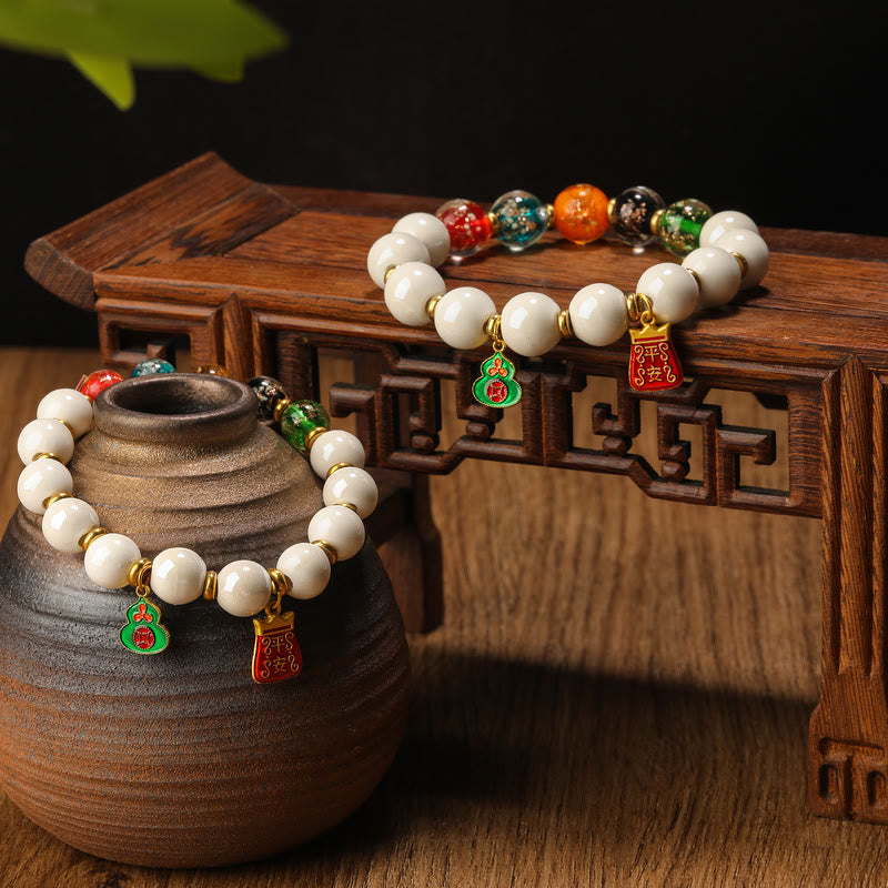 Weißes Perlen Armband mit bunten Anhängern auf Holz.