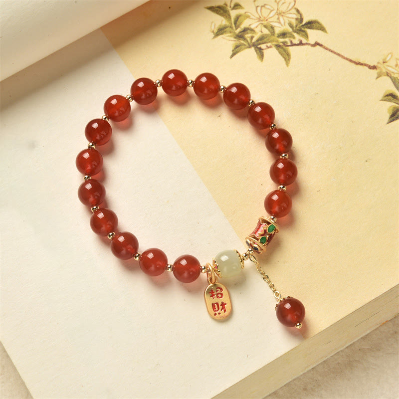 Armband Roter Achat Jade mit Segenanhänger auf heller Oberfläche