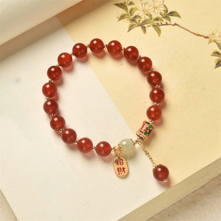 Armband Roter Achat Jade mit Segenanhänger auf heller Oberfläche