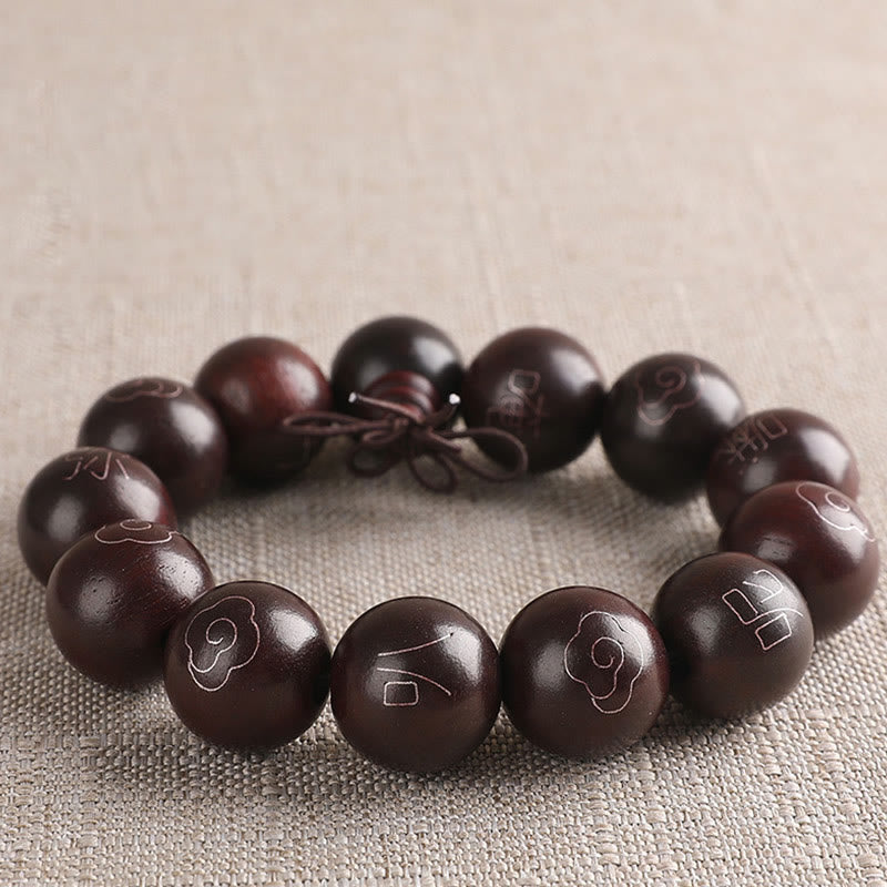 Dunkelbraunes Sandelholz Armband mit eingravierten Om Mani Padme Hum Symbolen elastisch.