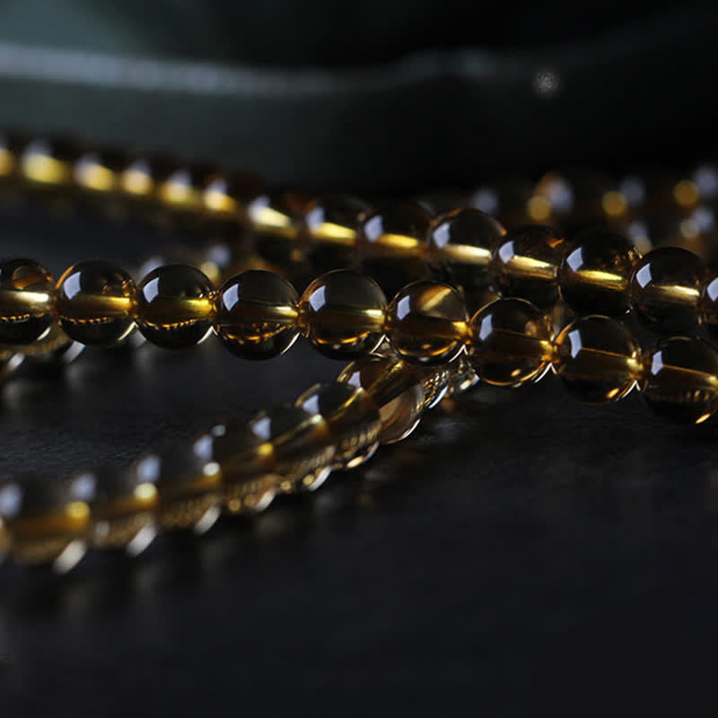 Goldene Citrin Perlen Armband Kette auf dunklem Hintergrund glänzend.