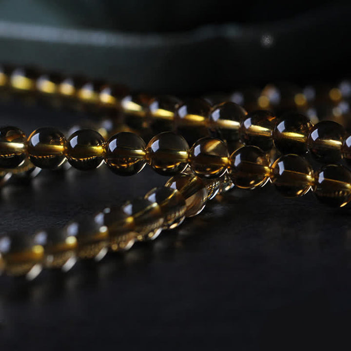 Goldene Citrin Perlen Armband Kette auf dunklem Hintergrund glänzend.