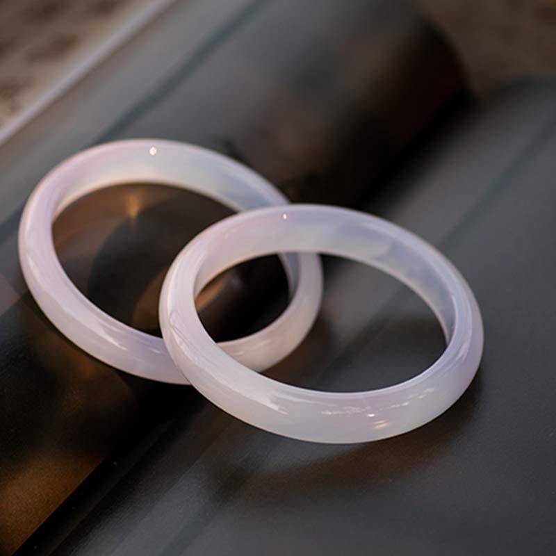 Armband – Harmonie aus Jade, zwei transluzente Ringe auf grauem Untergrund.