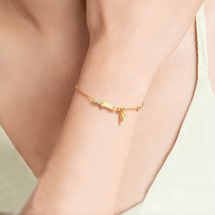 Goldenes Armband mit Plakette und Anhänger am Handgelenk getragen elegant