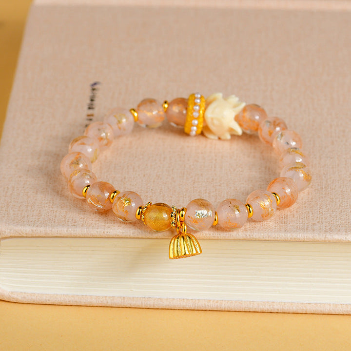 Armband Lotus – Glück mit apricot Perlen und goldenem Anhänger elegant.