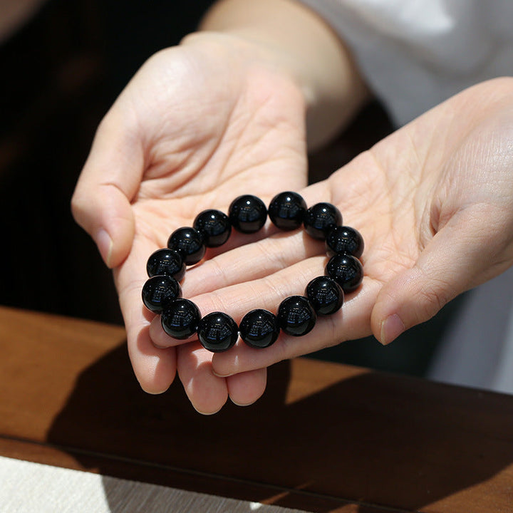 Armband Schwarzer Onyx – Glück elegantes Perlenarmband in Hand gezeigt