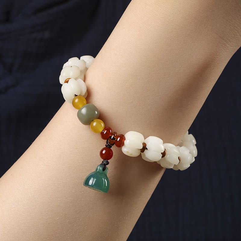 Armband mit weißen Perlen, roten Achat und grünem Anhänger am Handgelenk