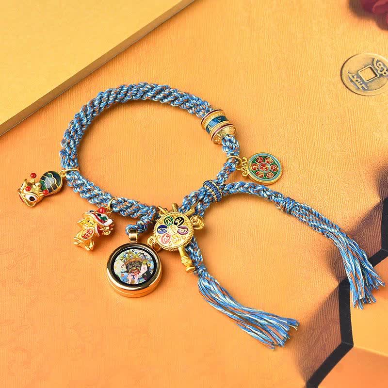 Armband – Glück & Wohlstand blaues Seil goldene Charms flach auf gelbem Hintergrund
