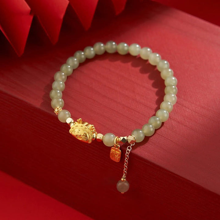 Jadegrün Armband mit goldenem Löwenkopf auf rotem Hintergrund elegant.