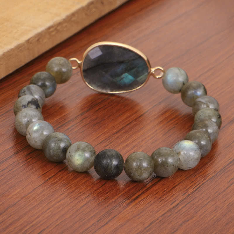 Armband Labradorit Mondstein mit goldenem Verschluss auf Holz.