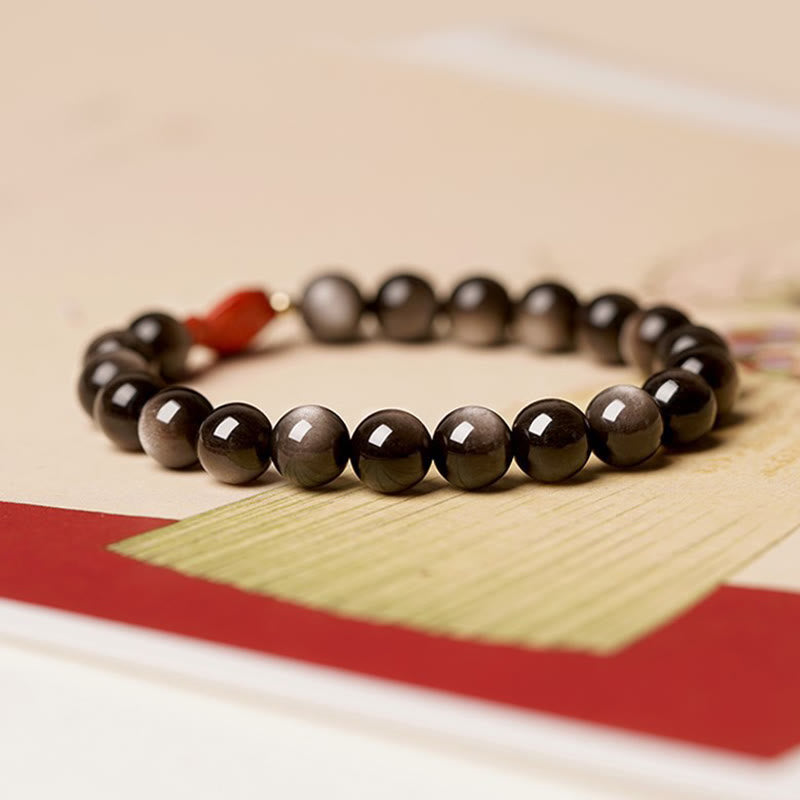 Obsidian Armband mit roten Akzenten auf Holzoberfläche elegant präsentiert