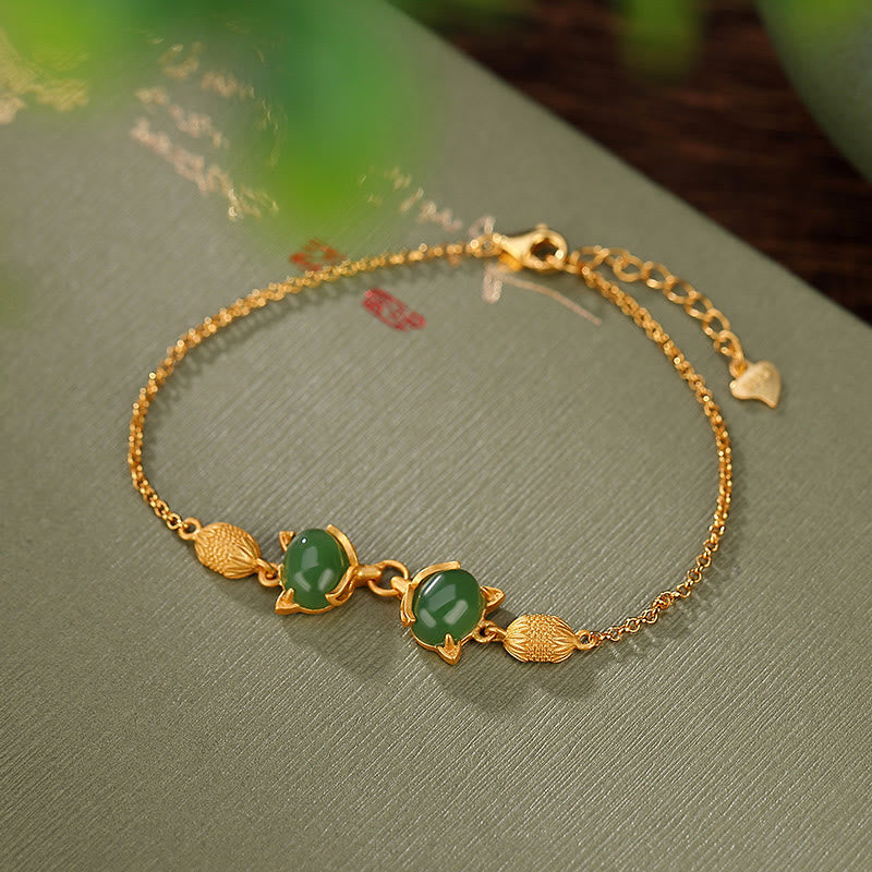 Goldenes Armband mit grüner Jade Fuchs Anhängern am Handgelenk.