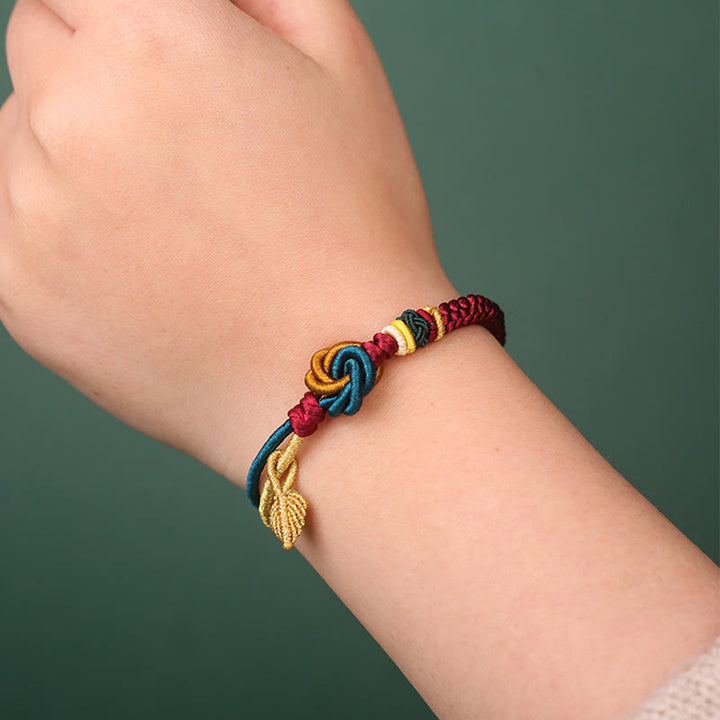 Tibetisches Armband am Handgelenk mit bunten Knoten und goldenem Blatt Glücksbringer