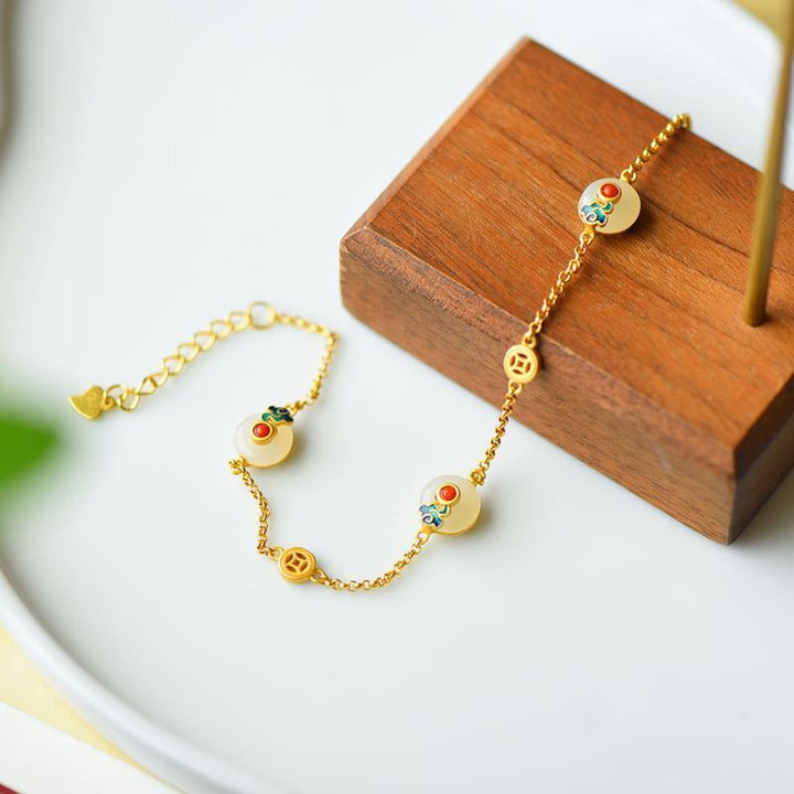 Goldenes Armband mit weißer Jade und bunten Steinen elegant präsentiert.