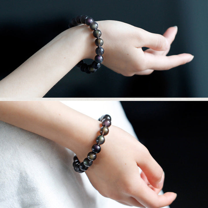 Armband Regenbogen Obsidian mit glänzenden Perlen am Handgelenk getragen
