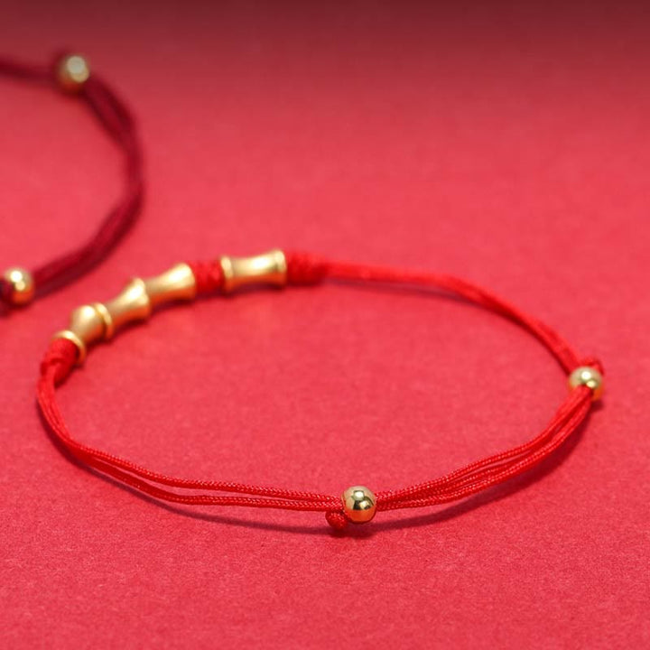 Rotes Seidenarmband mit goldenen Perlen elastisch verstellbar elegant.