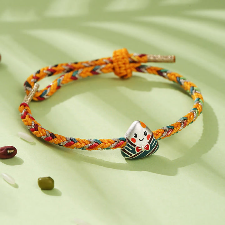 Buntes Armband mit Glückspuppe Charm auf grünem Hintergrund elegant.