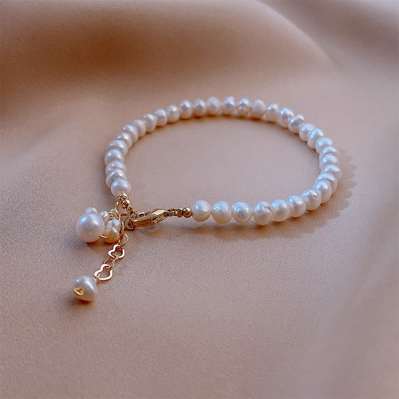 Weißes Perlenarmband mit goldenem Verschluss und Anhänger elegant.