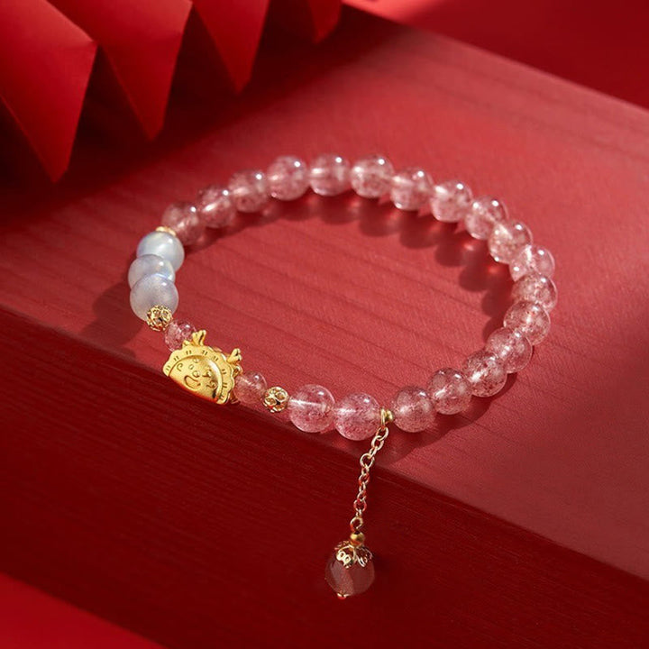 Rosenquarz Armband mit goldenem Fu-Zeichen Anhänger elegant präsentiert.