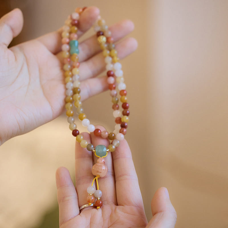 Mehrfarbiges Perlenarmband mit Jade-Anhänger in der Hand getragen.
