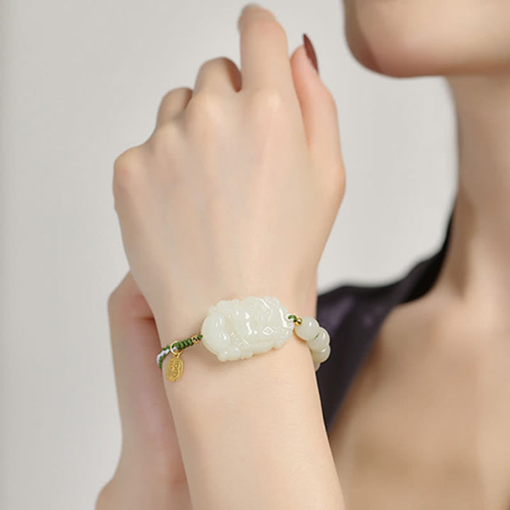 Weißes Jade Armband mit goldenem Anhänger elegant am Handgelenk getragen.