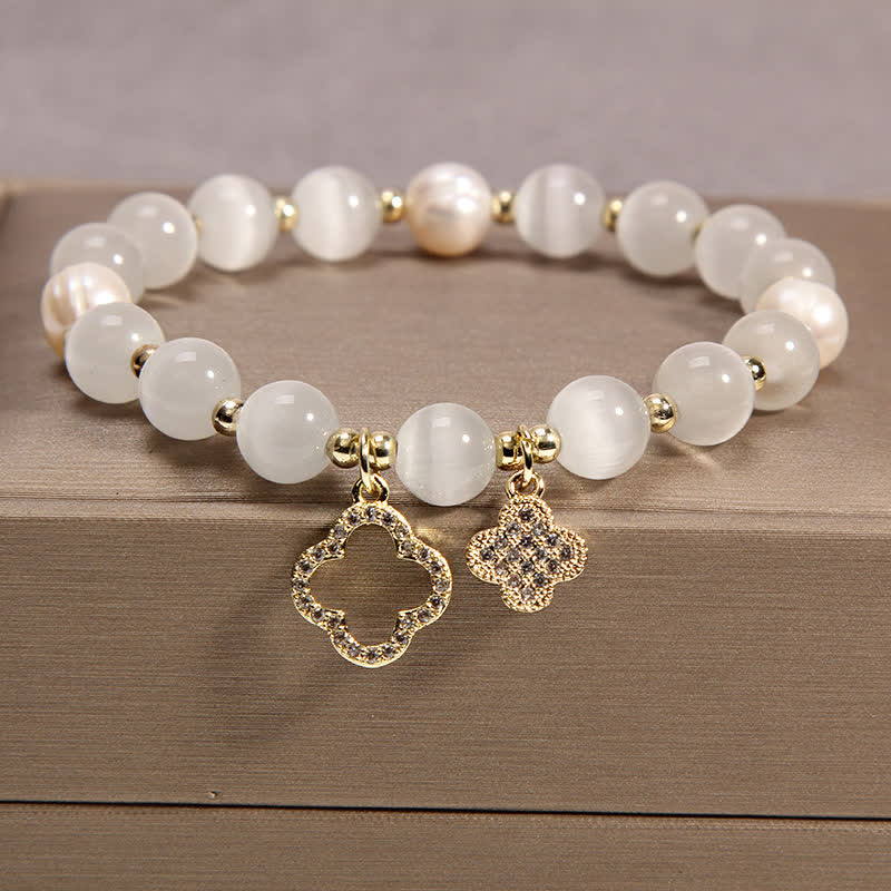 Weißes Perlen Armband mit goldenen Quatrefoil Charms Holzoberfläche