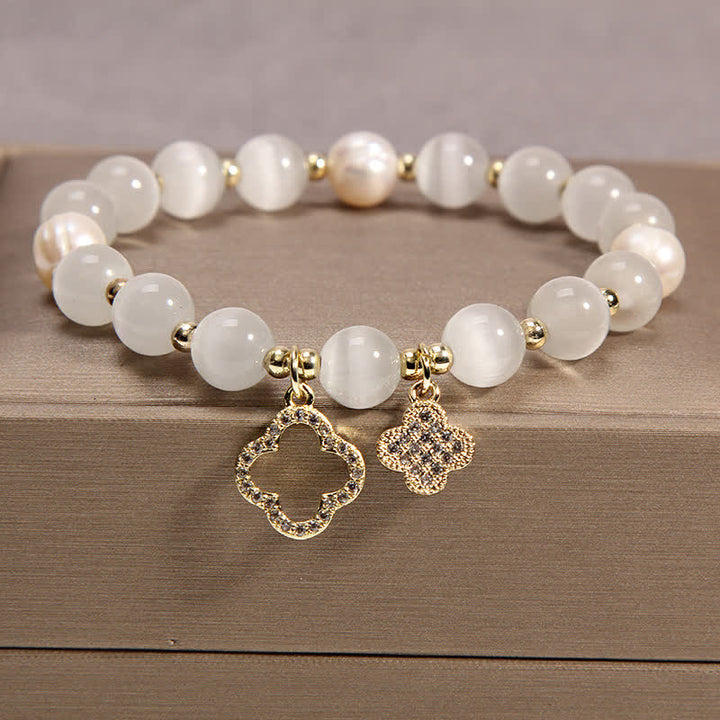 Weißes Perlen Armband mit goldenen Quatrefoil Charms Holzoberfläche