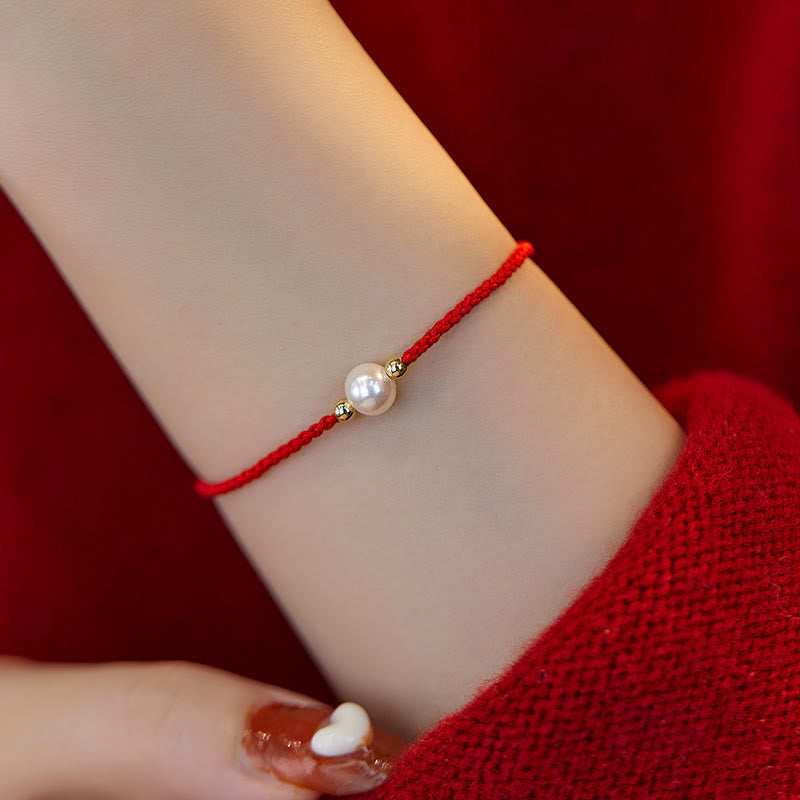 Rotes geflochtenes Armband mit Naturperle am Handgelenk getragen elegant
