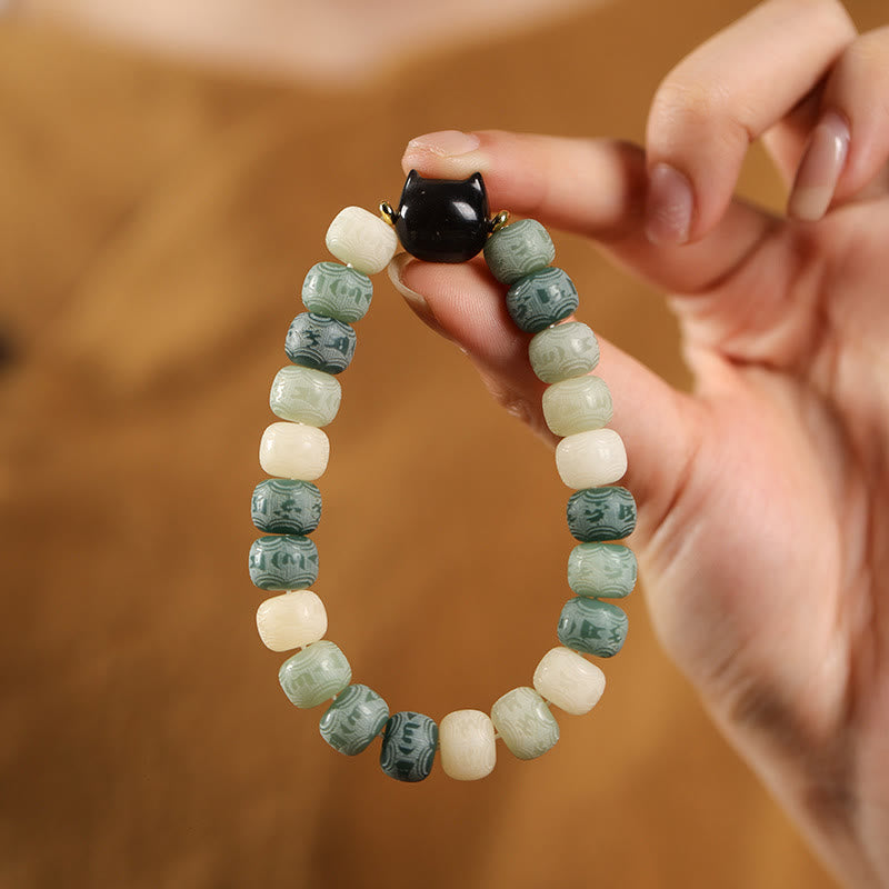Armband mit schwarzem Obsidian und grünen Steinen am Handgelenk getragen.