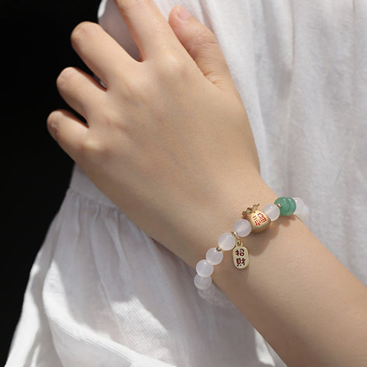 Armband mit weißen Perlen und grünem Stein am Handgelenk getragen