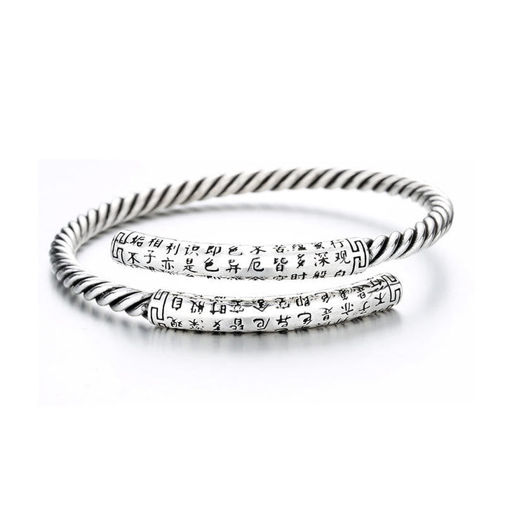 Silbernes Armband mit Herzsutra-Gravur, elegant gedreht, Handgelenk.