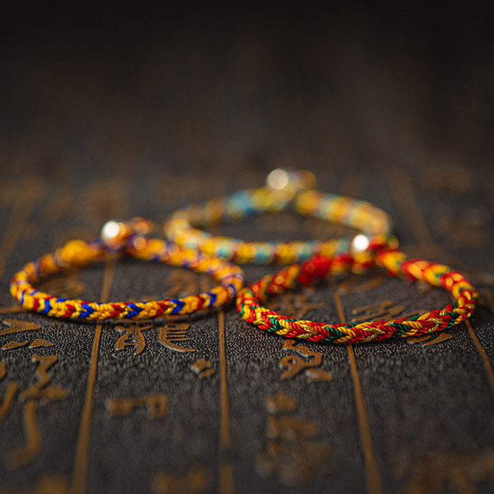 Bunte Glücksarmbänder auf Holzoberfläche, mehrfarbige Baumwolle, Armband – Glück & Erfolg