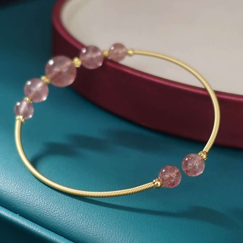 Armband Erdbeerquarz mit goldenen Perlen am Handgelenk getragen