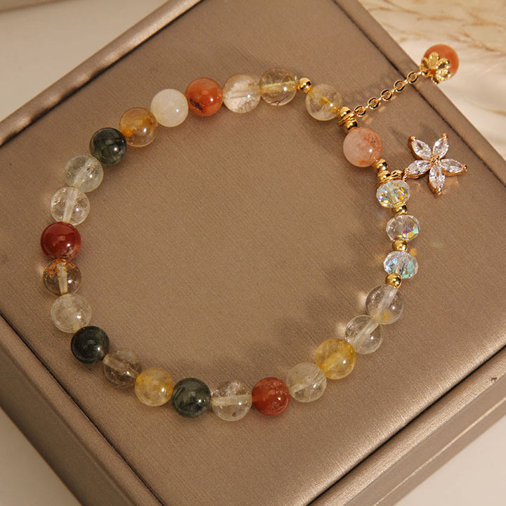Buntes Armband mit Rutilquarz, Zircon und Glückssteinen auf Beige.