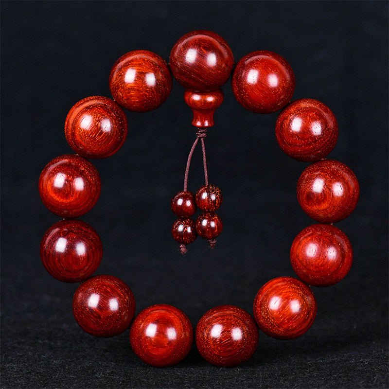 Rotes Sandelholz Armband mit glänzenden Perlen auf dunklem Hintergrund