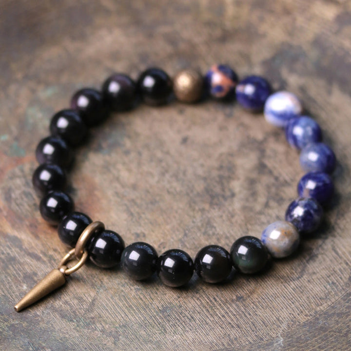 Schwarzer Obsidian Armband mit blauen Steinen und Metallanhänger.