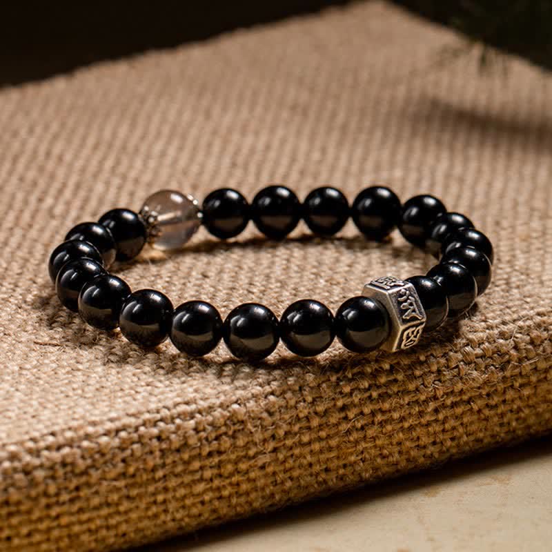 Schwarzes Obsidian Armband mit Silber-Akzenten auf beiger Unterlage elegante Gestaltung.