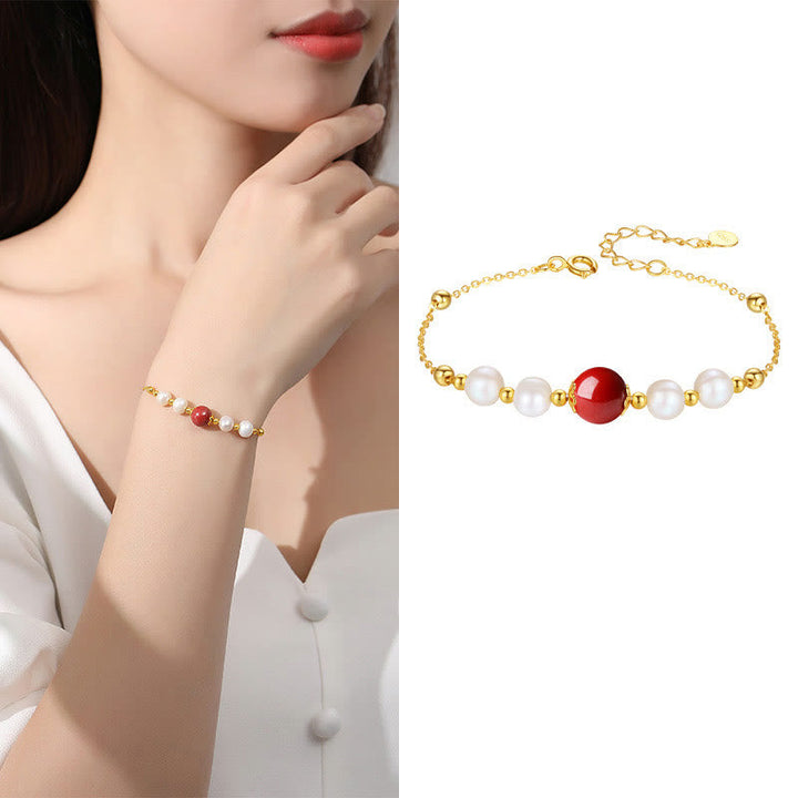 Goldenes Armband mit Perlen und rotem Zinnober Stein Handgelenk.