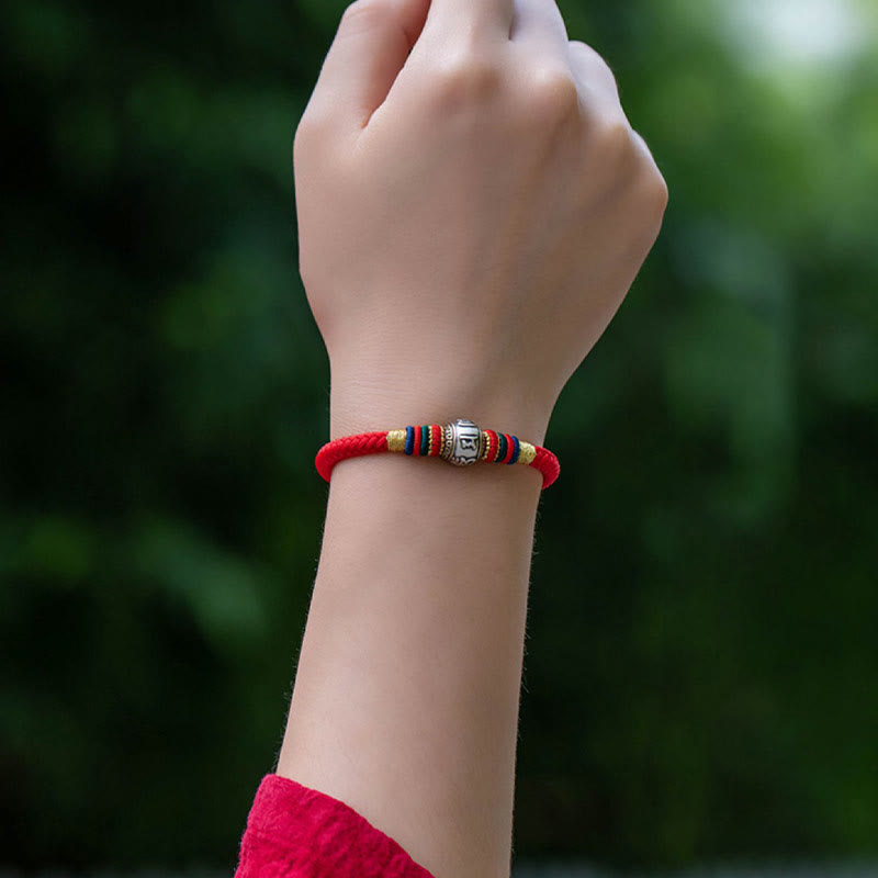 Rotes Armband mit Om Mani Padme Hum Charm am Handgelenk getragen.