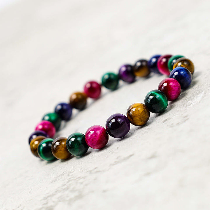 Armband Tigerauge – Mut mit bunten Natursteinen auf Marmor.