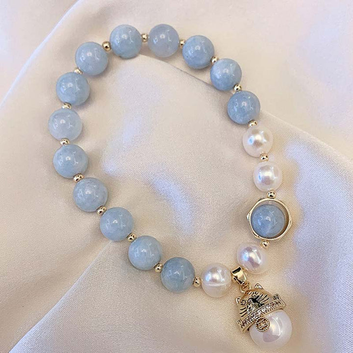 Armband Aquamarin Perle Katze – Glück & Heilung auf Creme Stoff präsentiert