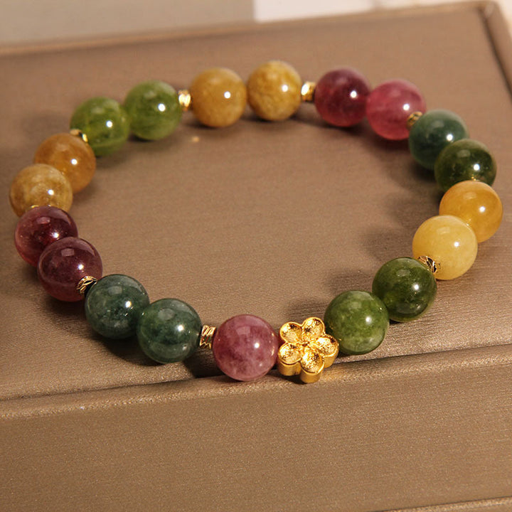 Buntes Tourmaline Armband mit goldener Blume auf beiger Oberfläche.