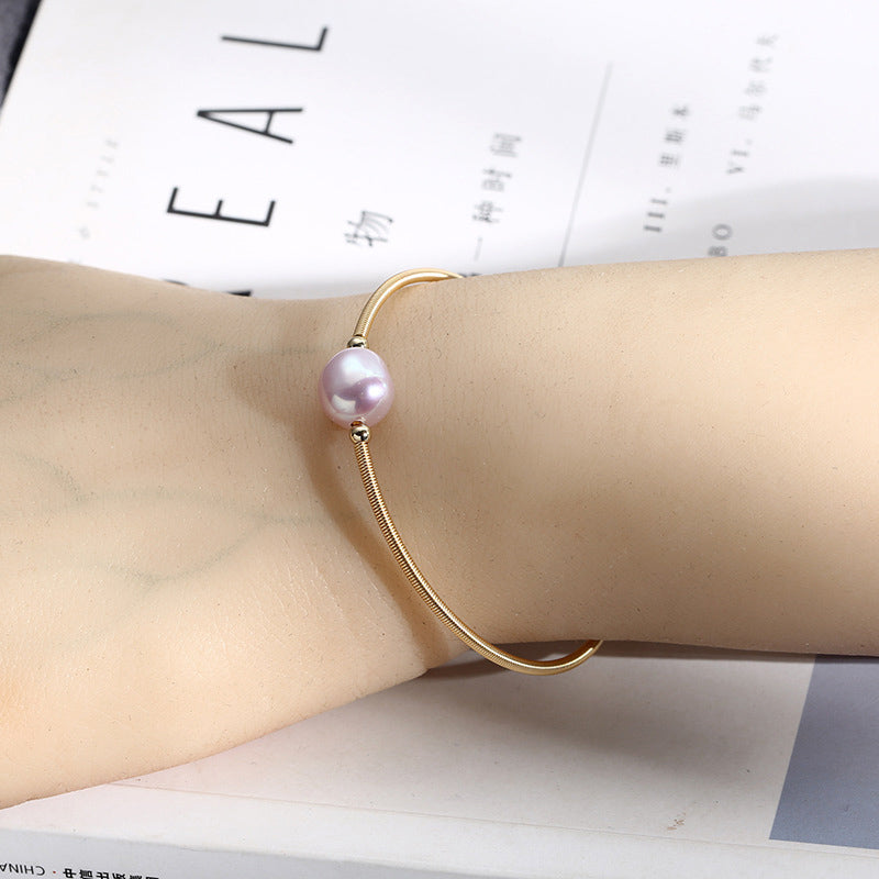 Armband Perle – Wohlstand goldfarben mit lila Perle am Handgelenk