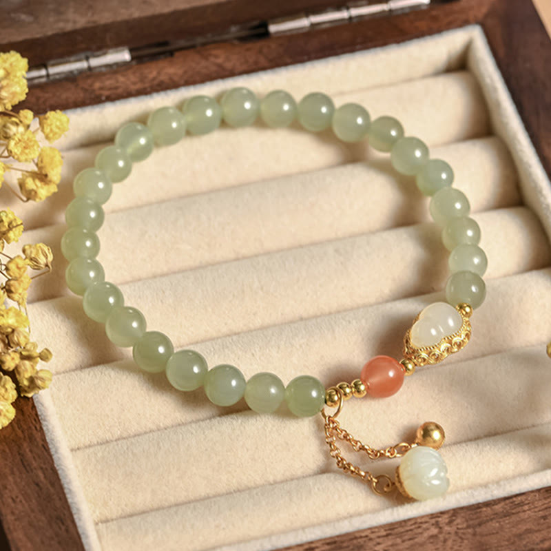 Jade Armband mit grünen Perlen, goldenen Akzenten und Anhänger elegant präsentiert.