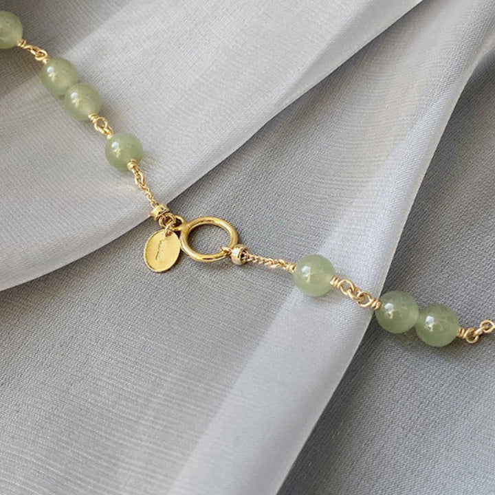 Jade Armband Gold mit grünen Steinen und Goldkette elegant.